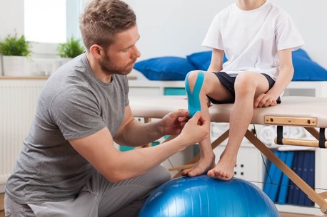 Physical therapist applying young patient medical tape