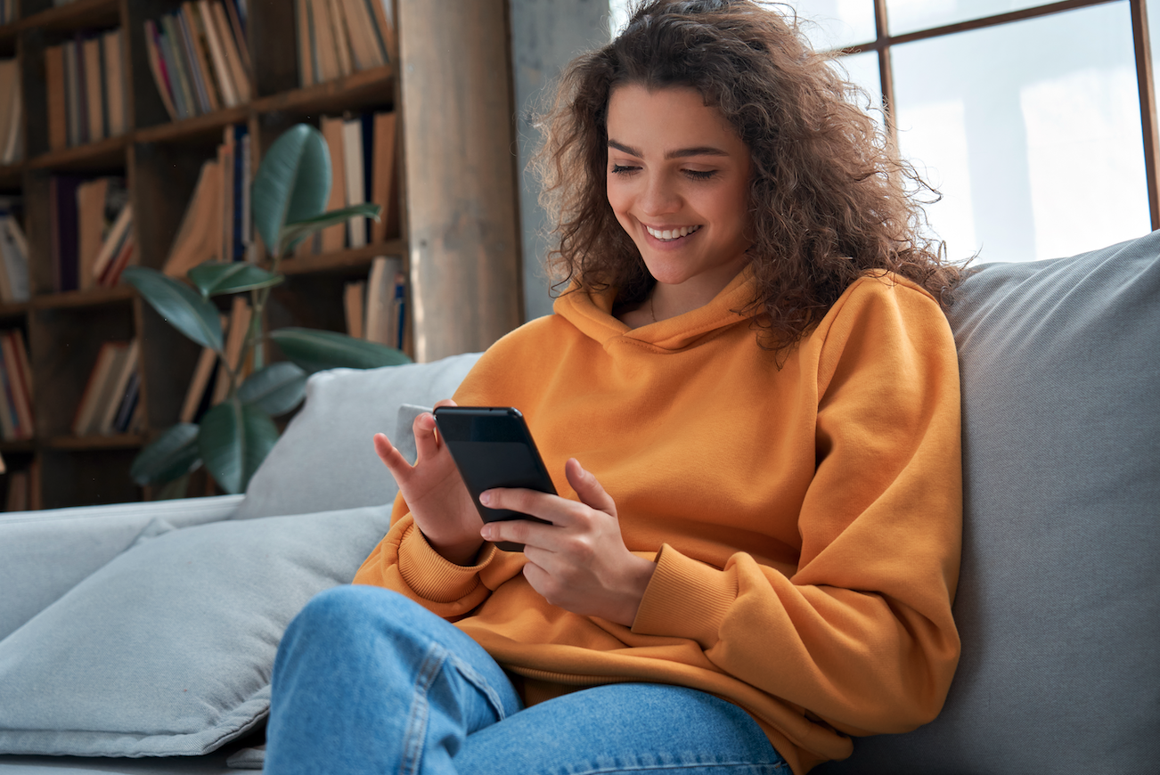 a woman sitting on the living room couch interacts with her phone