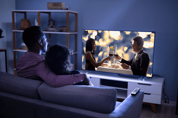a couple watches a romantic TV show on the TV in their living room