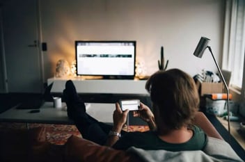 Person on their mobile device while watching a smart TV