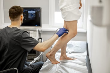 Ultrasound specialist is scanning the veins on a woman's leg, examining veins for varicose treatment