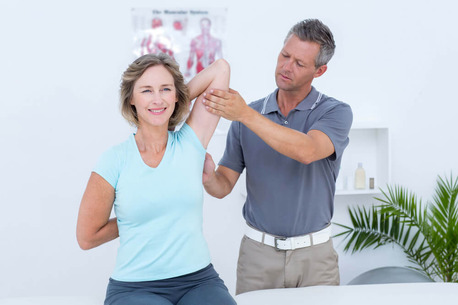 Woman stretching her arms with her doctor in medical office