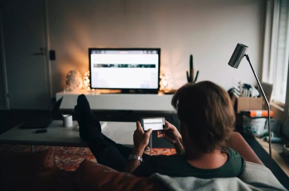 Person on their mobile device while watching a smart TV
