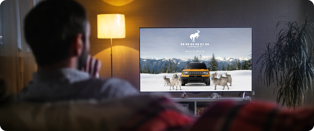 man watching automotive ctv ad on tv