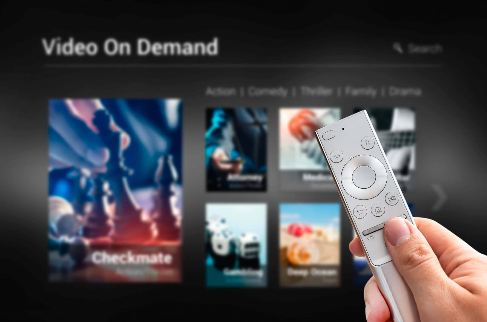 a hand holds a white tv remote against a video on demand menu that offers various types of streaming content